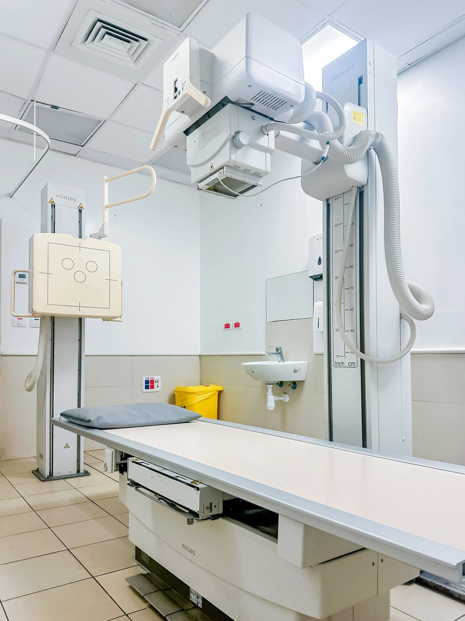 Clean, modern X-ray room with an imaging table and wall-mounted detector